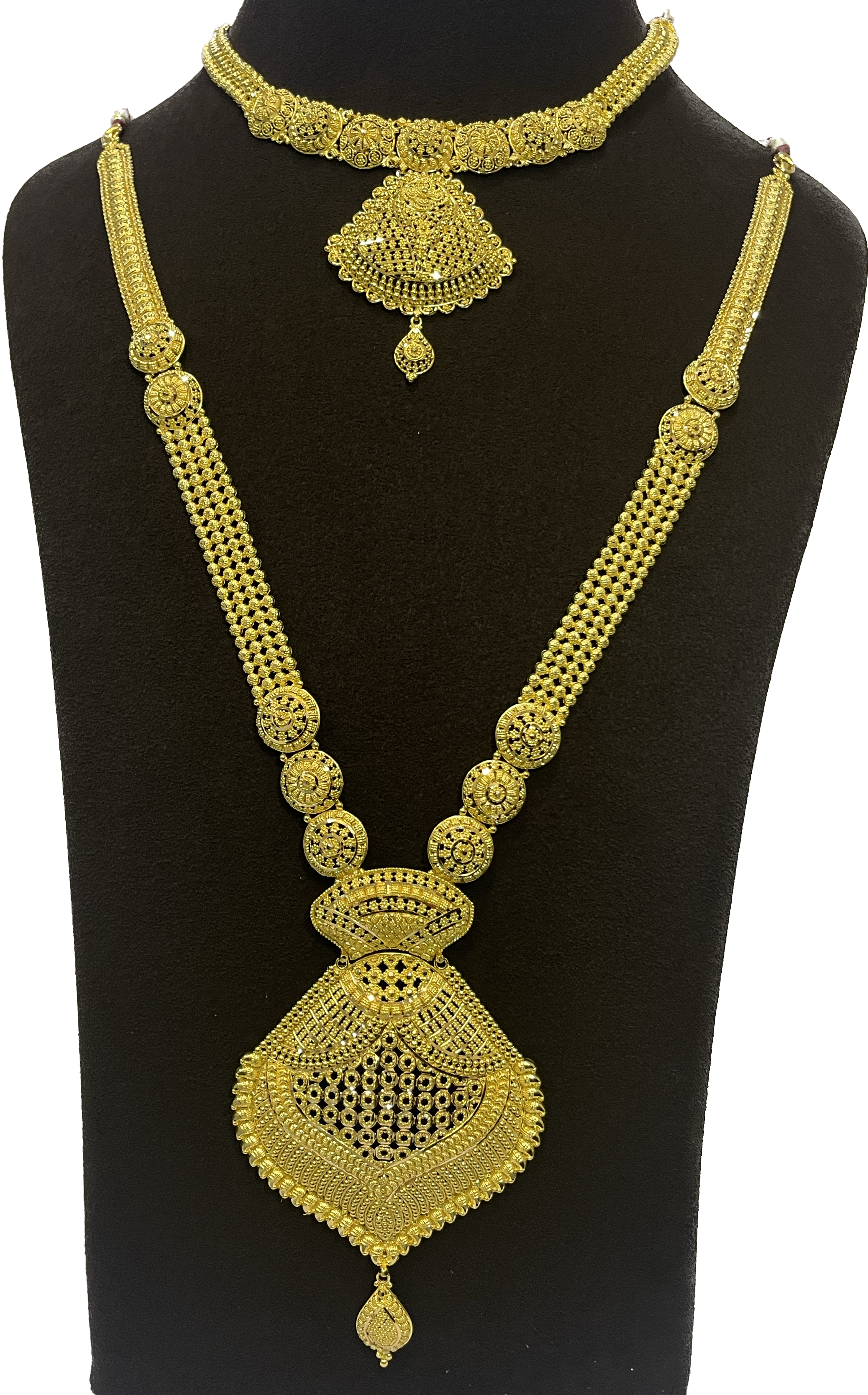 Two ornate necklaces with detailed pendants on a dark display bust.